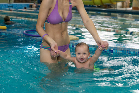 快乐的孩子，一个可爱的小女孩，在炎热的夏天一天和她妈妈在海洋中游泳