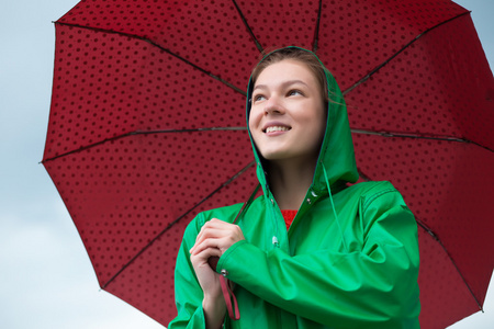 在阴云密布的天空背景打着伞的雨衣的女人