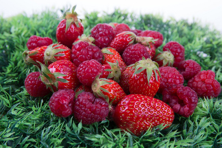 成熟的草莓和覆盆子查出的绿色背景