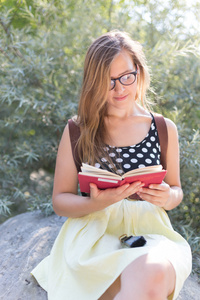 可爱的年轻女子坐在岩石上，对本书的性质