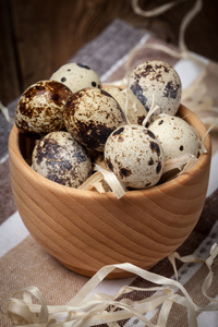 在一个木制的桌子上的木碗生鹌鹑蛋