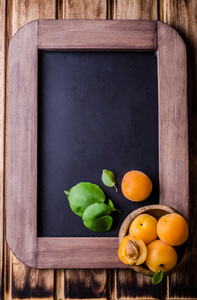 新鲜成熟仁用杏木碗上老式石板粉笔板背景。选择性的焦点。与地方为一些文本的背景。顶视图