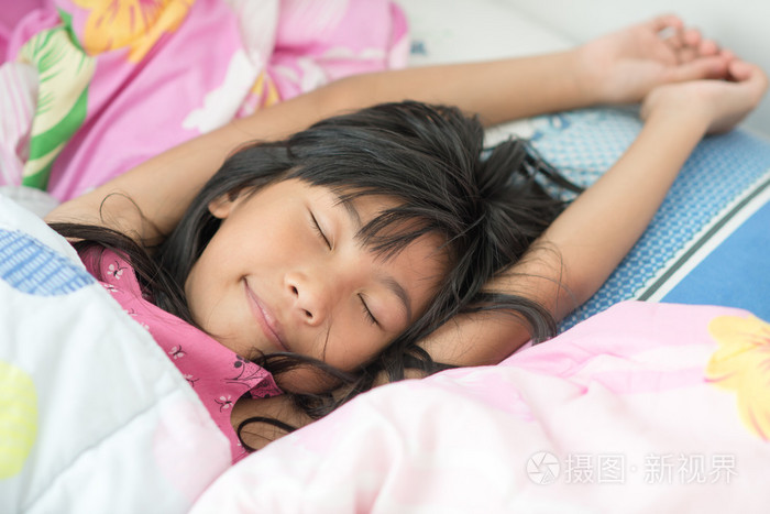 亚洲女孩睡在床上盖上条毯子