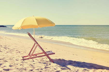 把黄色的雨伞和木椅上大西洋沙滩