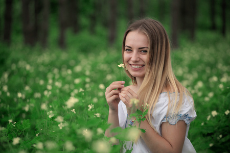 年轻漂亮的女孩穿着白衬衫，绿色森林背景特写
