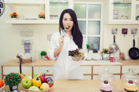 美丽的年轻女子，在厨房里吃健康的沙拉