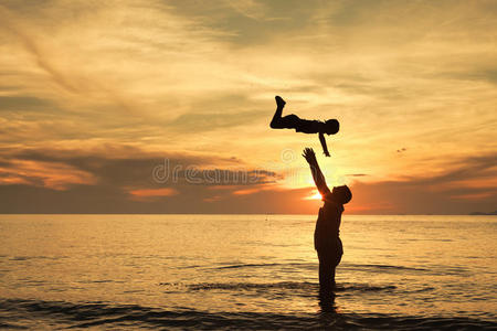 父亲和儿子在日落时在海滩上玩耍。