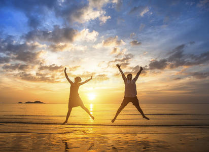 一对相爱的夫妇在一次令人惊叹的日落中跳上海滩。 幸福。