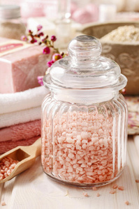 白色木制桌子上的粉红色海盐玻璃瓶