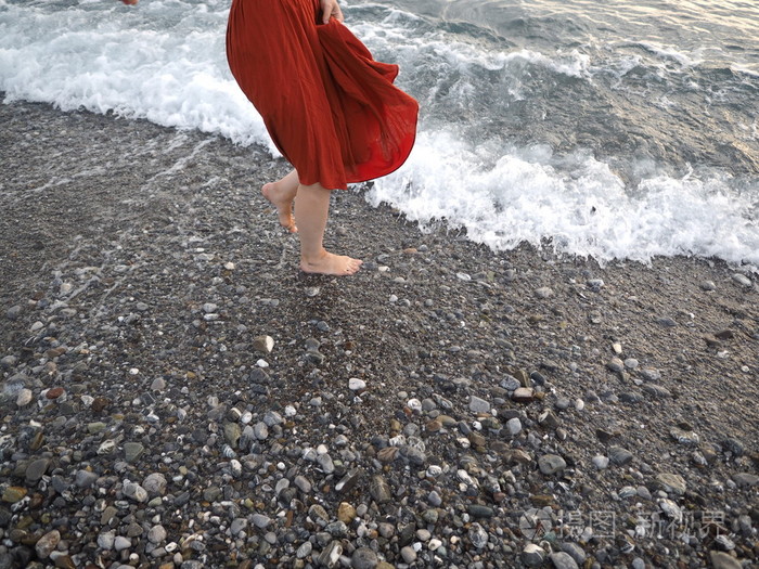 在女孩赤脚在岸边的红裙子