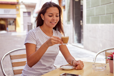 放松的女孩在街边咖啡馆喝咖啡图片