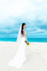 美丽的未婚妻穿着白色婚纱，白色的大火车和婚礼花束站在海边