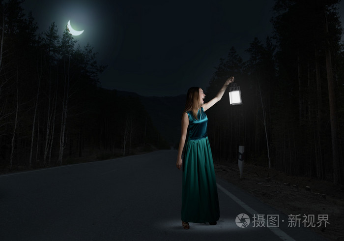 女人用灯笼在黑暗中行走