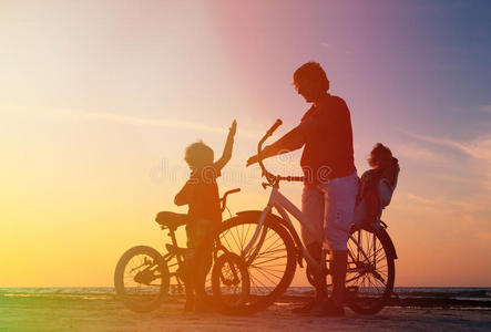父亲和两个孩子在日落时骑自行车