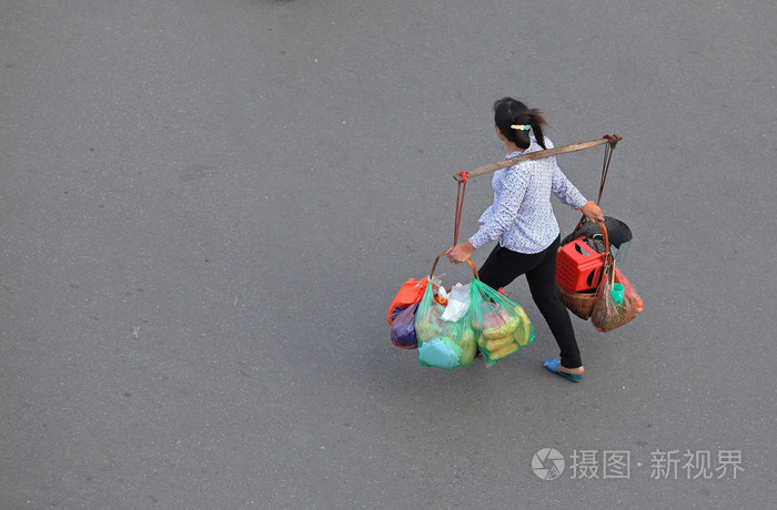 购物后的女人背着一根棍子背着很多包裹