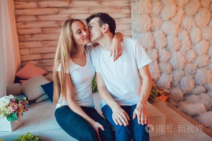 在坐的爱和人的脸颊上亲吻女孩的年轻夫妇