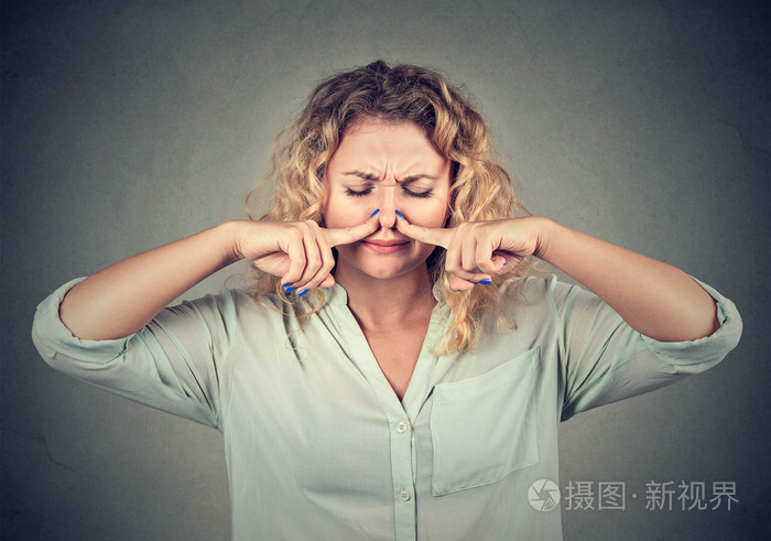女人用手指捏着鼻子,看着厌恶的东西
