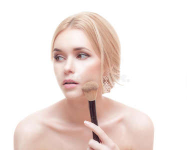 一个女人在脸上涂上干燥的化妆品色调基础的特写肖像