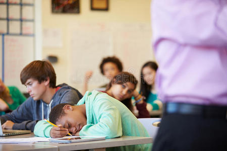 无聊的高中学生瘫倒在教室的桌子上