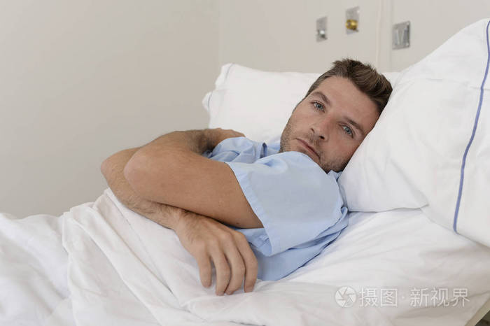 年轻有耐心的人躺在医院的床上休息累了看难过和沮丧