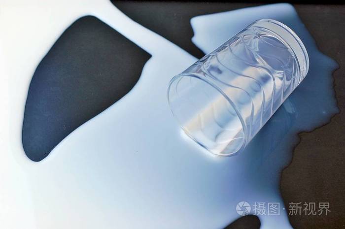 白洒了的牛奶与黑色背景上的玻璃