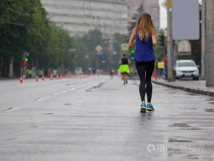 年轻的女人在雨中奔跑