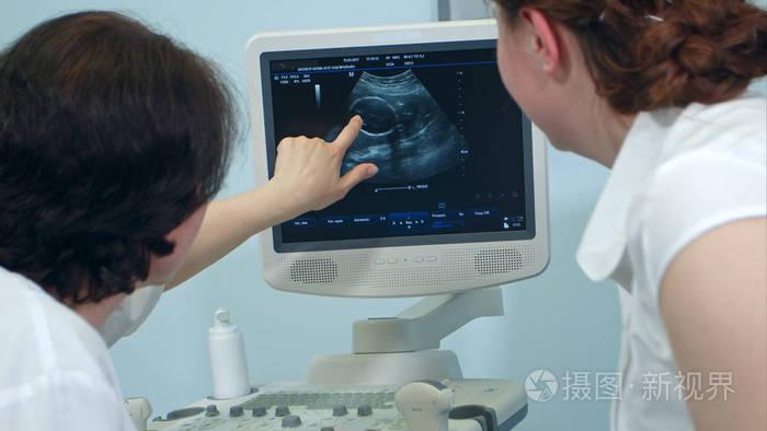 妇科医生和孕妇看超声显示胎儿