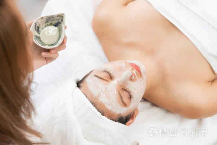 美丽的女人有一个面部美容擦洗治疗从专业皮肤科医生在健康水疗.