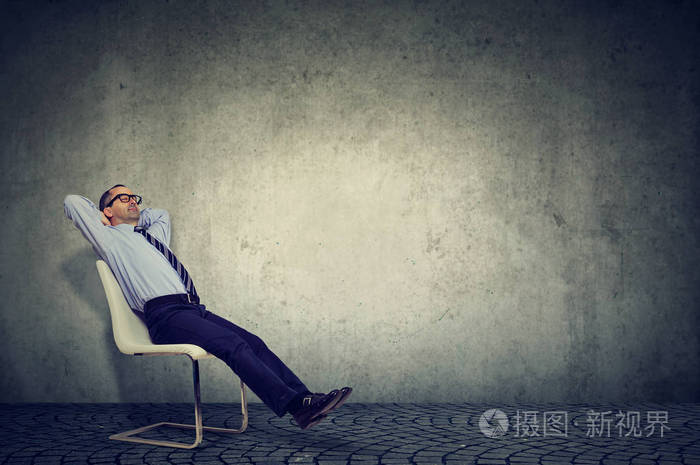 穿着正式服装的人坐在椅子上,双手背着头享受休息
