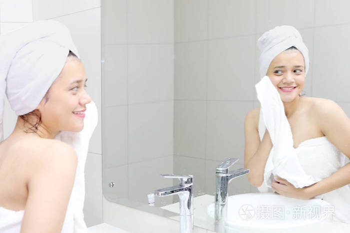 一个快乐的女人洗澡后用毛巾洗脸的照片