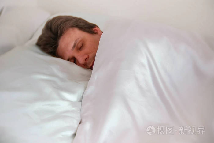 男人躺在床上独自睡在毯子下.侧面视图