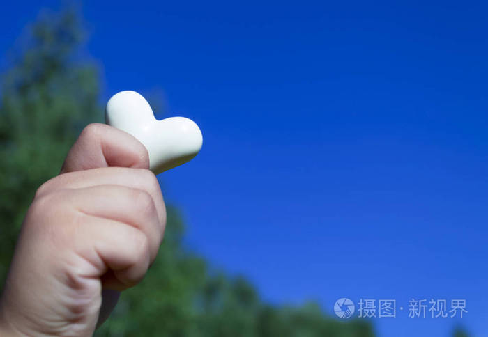白色的心在一个孩子的手中对抗蓝天
