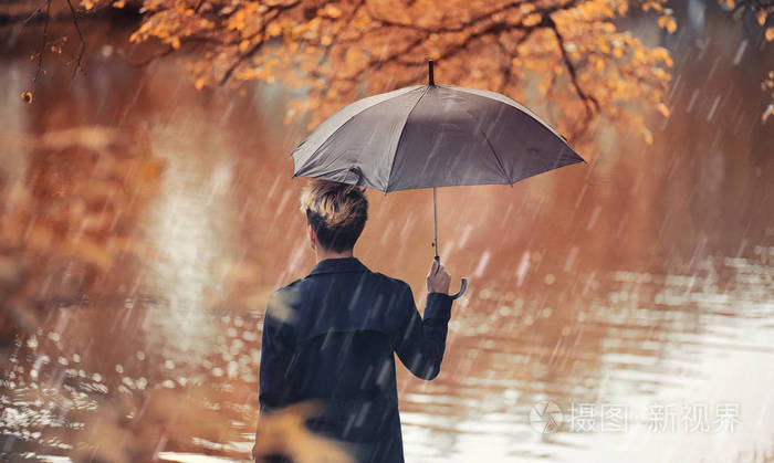 秋天下雨的天气和一个年轻的人用雨伞