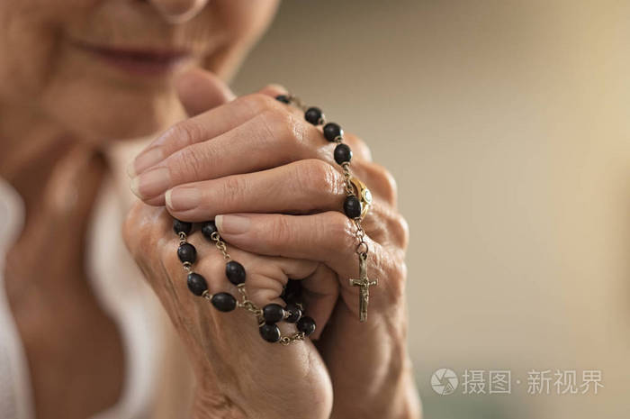 基督教高级妇女的特写双手捧着念珠,在祈祷上帝的同时钉十字架.