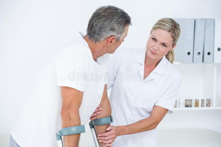 医生帮她的病人用拐杖走路