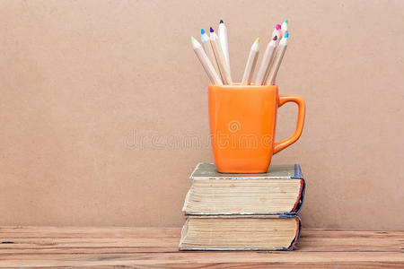 书塔和带彩色铅笔的橙色杯子