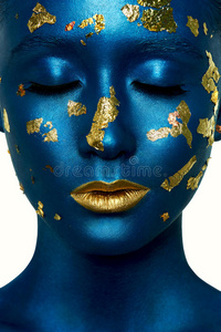 美丽的时尚女孩闭着眼睛，蓝色的油漆在皮肤上