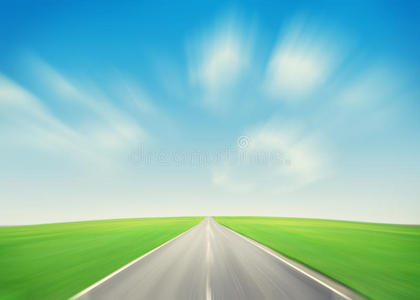 沥青路穿过绿色的田野和蓝天