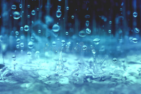 蓝色色调的特写雨水滴落到在雨季
