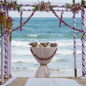 热带沙滩上用鲜花装饰的结婚拱门，户外海滩婚礼设置