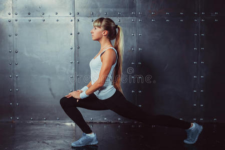 运动员女人在健身房伸展腿做健身