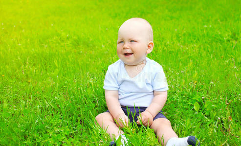 宝贝在阳光明媚的夏天坐在草地上