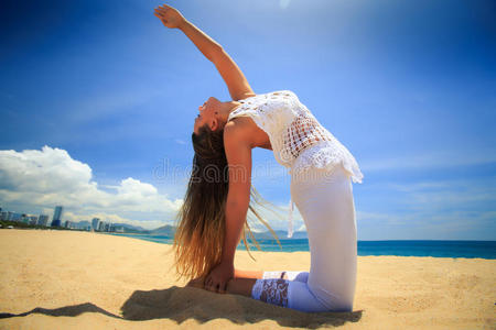 金发女孩穿着蕾丝瑜伽，阿莎娜车轮后弯在海滩上