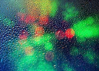 玻璃上的雨滴与散焦的灯。 抽象模糊