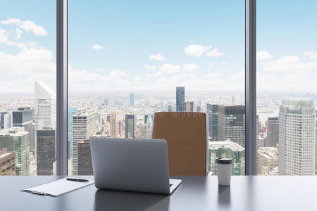 一个现代全景办公室的工作场所，有纽约的景色。 一张灰色的桌子，棕色的皮革椅子。
