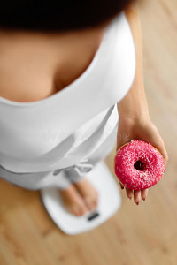 饮食概念。 女人拿着甜甜圈。 减肥。 节食