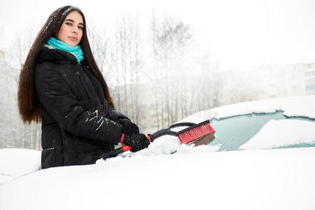 美丽的年轻有趣的女人把雪从她的车里移走