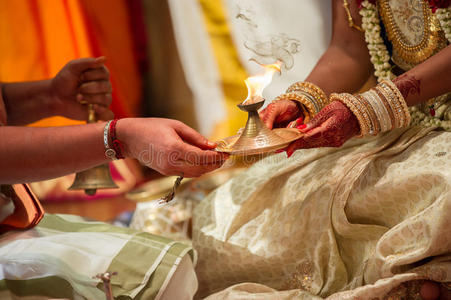 新娘在泰米尔印度教婚礼上接受牧师的灯