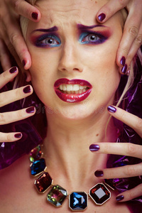 美丽的女人用创造性的化妆，许多手指在脸上紧贴