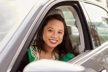 女性亚洲司机通过侧窗看着相机